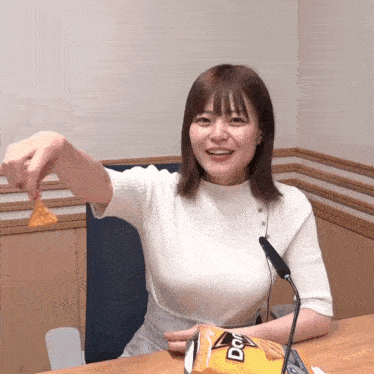 a woman in a white sweater is holding a bag of doritos chips