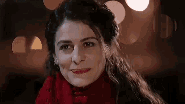 a woman is wearing a red scarf and smiling .