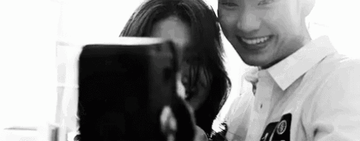 a black and white photo of a man and a woman taking a selfie .