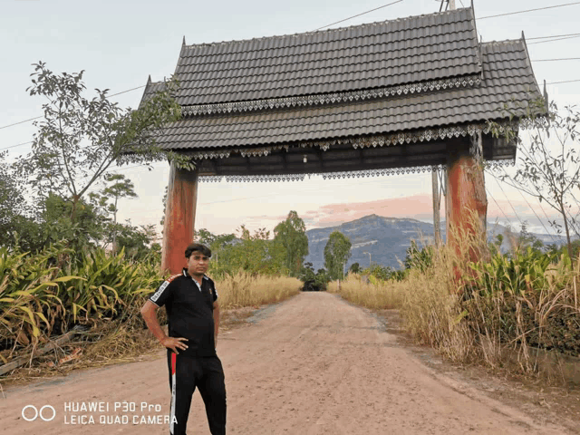 a huawei p30 pro leica quad camera takes a picture of a man standing in front of a wooden archway