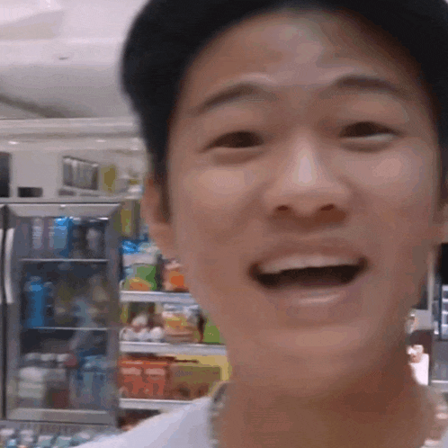 a man in a hat is smiling in front of a refrigerator in a store