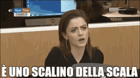 a woman is sitting in front of a computer with the words e uno scalino della scala written on the bottom