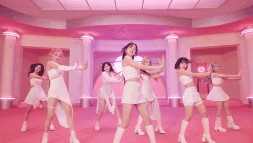 a group of women are dancing in a room with pink columns