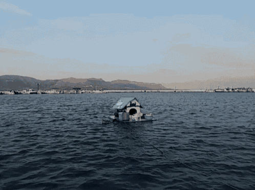 a small boat in the middle of a body of water with mountains in the distance