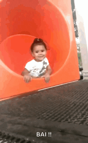 a little girl is sliding down an orange slide and the caption says bai !!