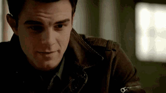 a close up of a man wearing a brown jacket and a tie .