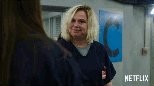 a woman in a prison uniform is smiling in front of a sign that says netflix