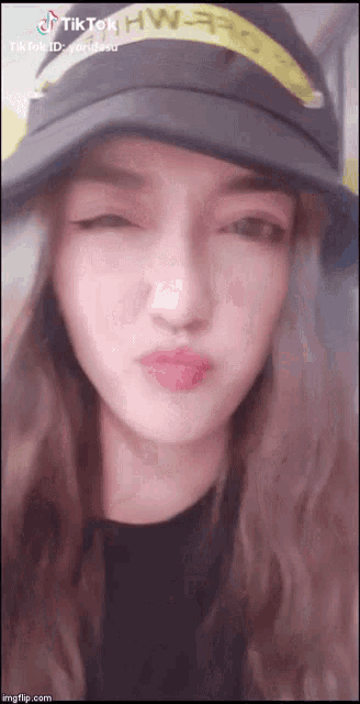 a woman wearing a hat with the word hw on it makes a funny face