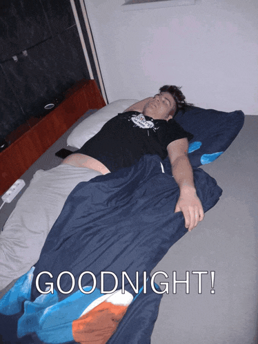 a man in a black shirt is laying on a bed with the words " goodnight " above him