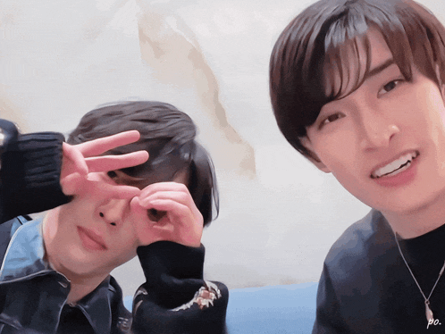 two young men are making a heart with their hands