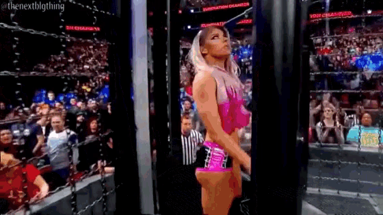 a female wrestler is standing in front of a crowd in a ring .