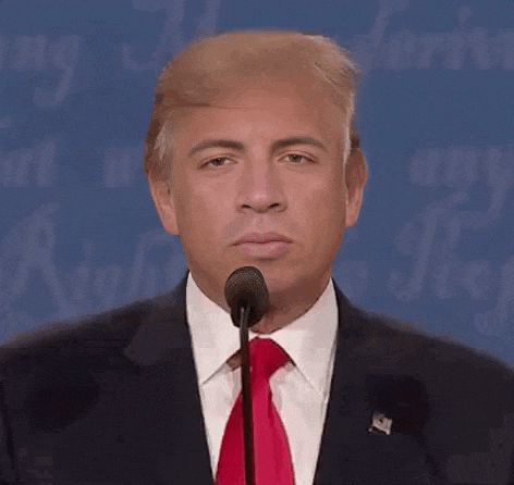 a man in a suit and red tie is speaking into a microphone .