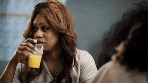 a woman is drinking orange juice from a plastic cup .