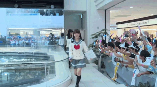 a girl in a sailor uniform is walking in front of a crowd of people
