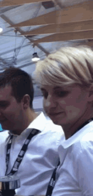 a woman wearing a lanyard that says ' a ' on it is sitting next to a man