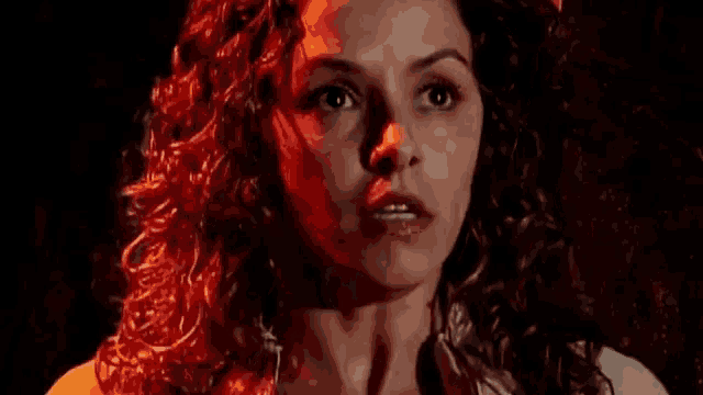 a close up of a woman 's face in a dark room with red lights .