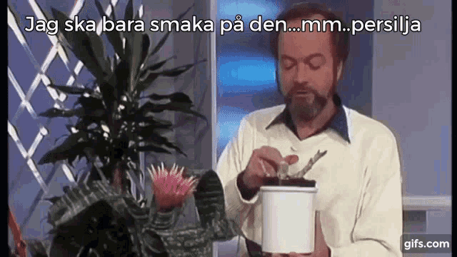 a man with a beard is holding a potted plant and says jag ska bara smaka på den ... mm ... persilja