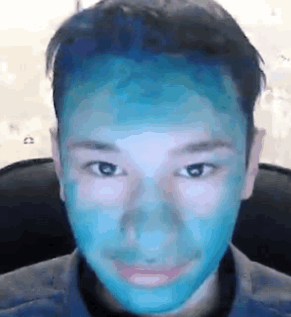 a young man with a blue mask on his face is sitting in a chair .