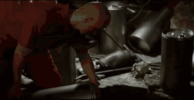 a bald man in a red shirt is standing in a room surrounded by pots .