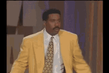 a man in a yellow suit and tie is standing in front of a staircase .