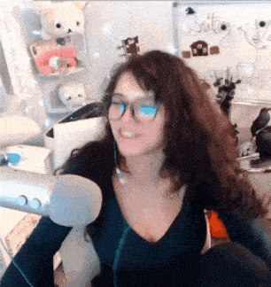 a woman wearing glasses and a black shirt is sitting in front of a microphone .