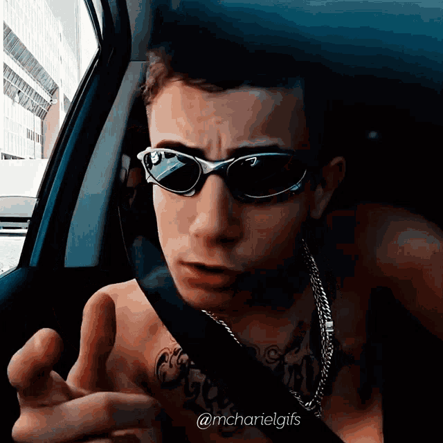 a man wearing sunglasses is sitting in a car with the hashtag @mcharielgifs below him