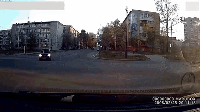 a car is driving down a street with a marubox watermark on the dashboard