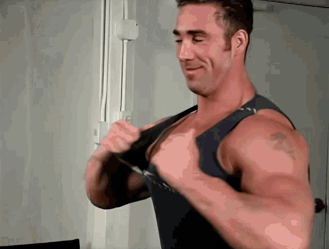 a man with a tattoo on his arm is wearing a black tank top