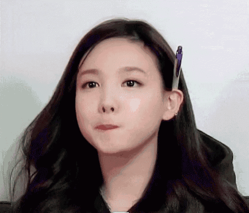 a woman is holding a pen in her ear and making a funny face .