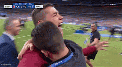 a man with a france lanyard around his neck is hugging another man on a soccer field