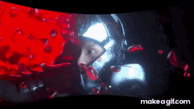 a man in a helmet is surrounded by red liquid and blood .