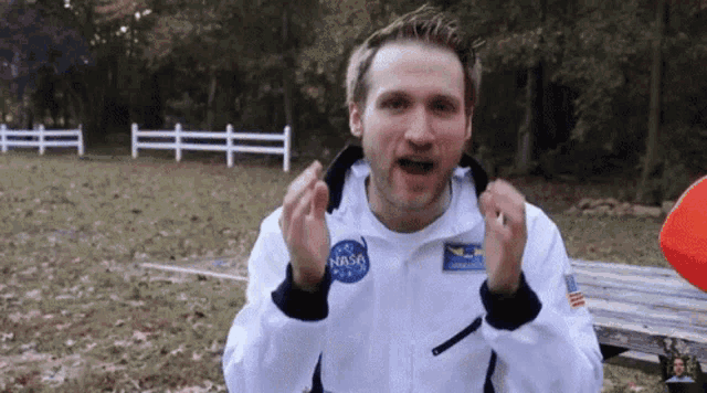 a man is wearing a nasa jacket and making a funny face .