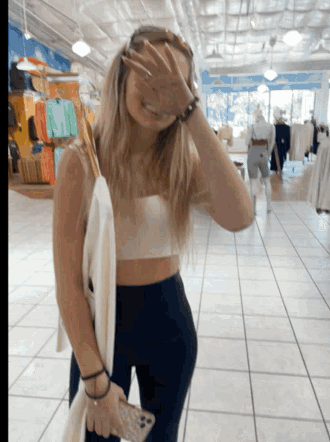 a woman covering her face with her hand while holding a phone