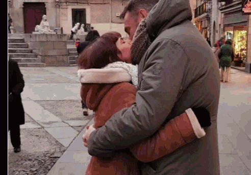 a man in a green jacket kisses a woman in a brown coat