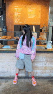 a woman standing in front of a bakery counter with a menu behind her