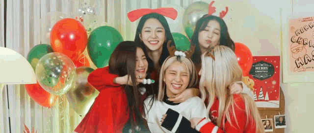 a group of young women are posing for a picture in front of balloons and a sign that says merry christmas