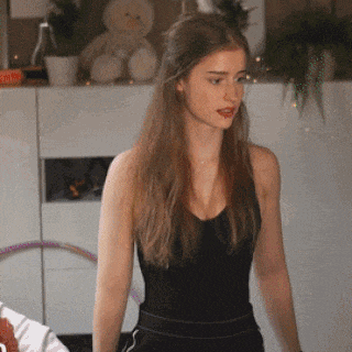 a woman wearing a black tank top is standing in front of a white cabinet