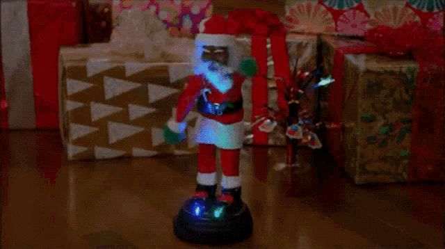 a statue of santa claus is standing in front of a pile of gifts