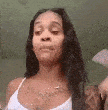 a woman with long hair and a tattoo on her chest is making a face .