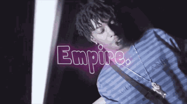 a man in a striped shirt is standing in front of a sign that says " empire "