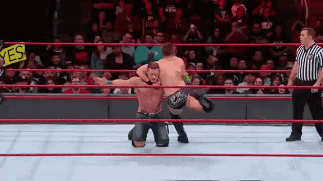 two wrestlers are in a ring with a sign that says yes on it