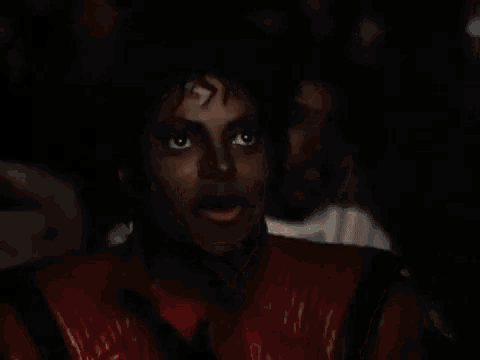a man in a red jacket is smiling in a dark room .