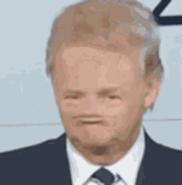 a man wearing a suit and tie is making a funny face .