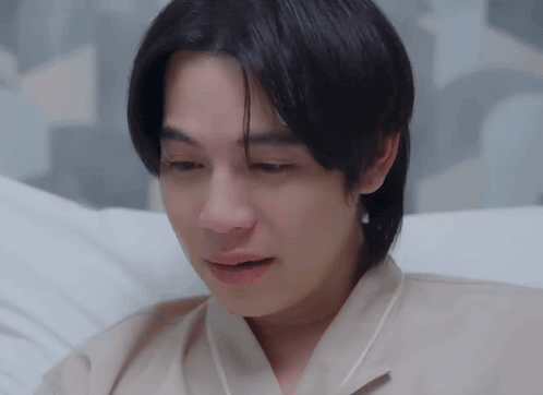 a young man is laying on a bed with his eyes closed and his mouth open