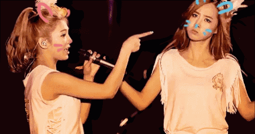 two women are standing next to each other and one is pointing at the other 's face