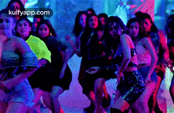 a group of women are dancing together in a dark room in a club .