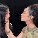 two women are touching each other 's faces in a room .