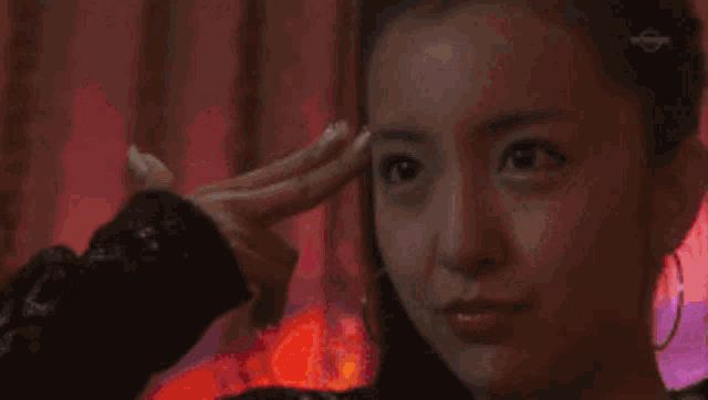 a woman is making a peace sign with her finger on her forehead