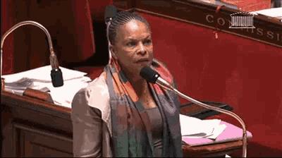 a woman is speaking into a microphone in front of a sign that says commiss