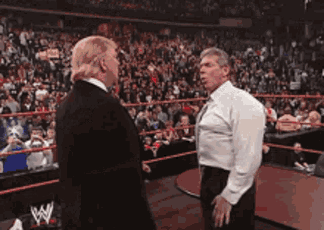 two men are standing next to each other in a wrestling ring with the letter w on the ring